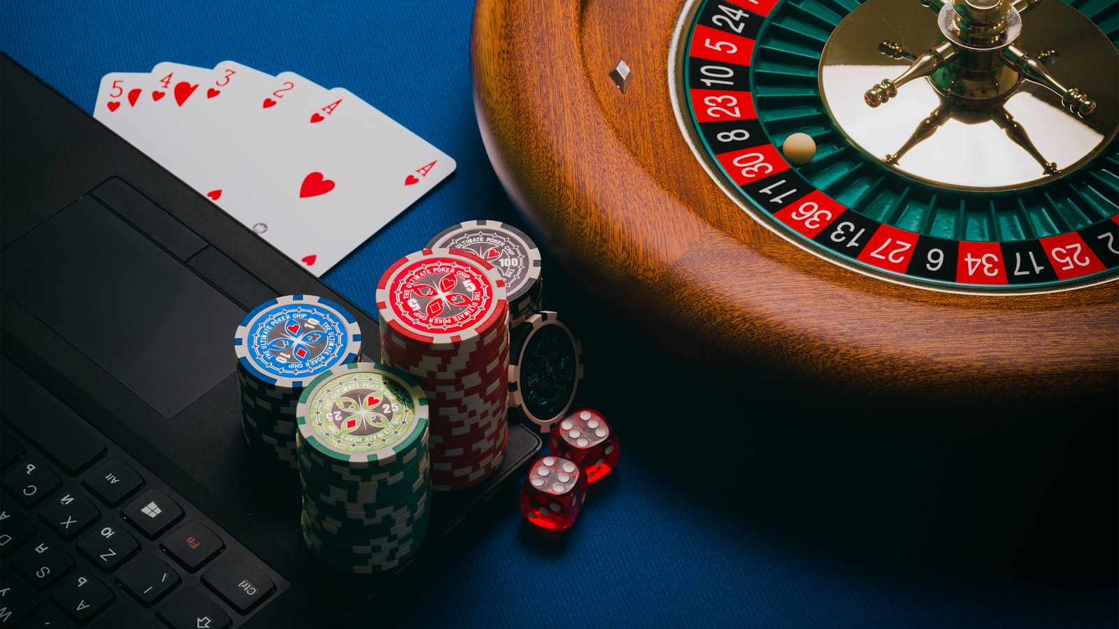 Online casino on a laptop with chips, cards, dice and a roulette wheel